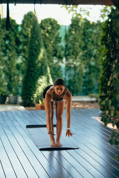 Mujer joven realiza uttanasana Practicar yoga sola