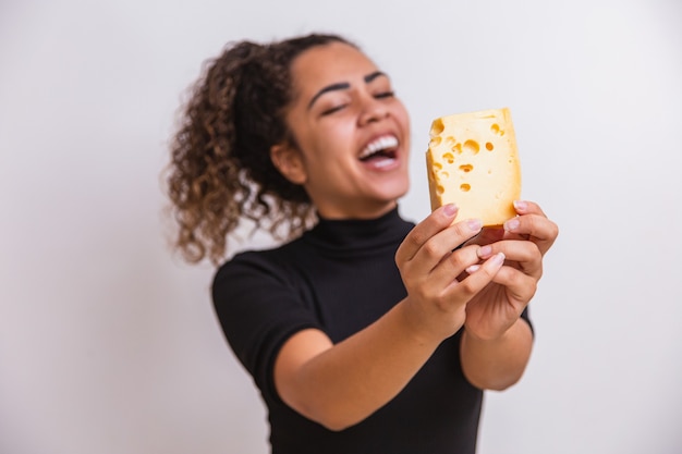 Mujer joven con una rebanada de queso en la mano. mujer comiendo queso parmesano. centrarse en el queso