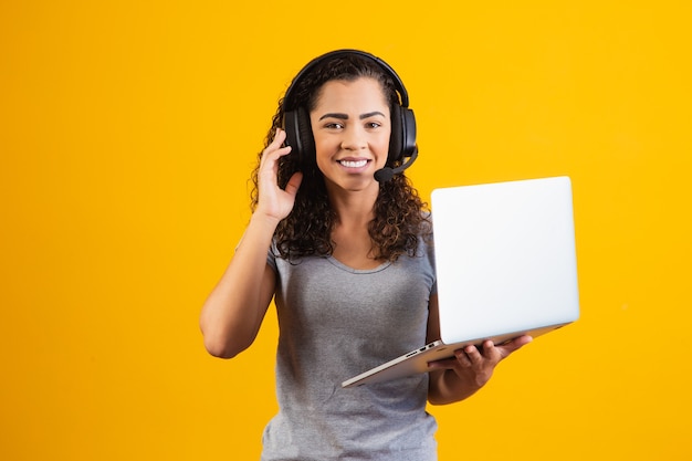 Mujer joven recepcionista que trabaja con portátil y auriculares.