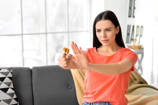 Mujer joven rechazando cigarrillos en casa. Concepto de rechazo por mal hábito