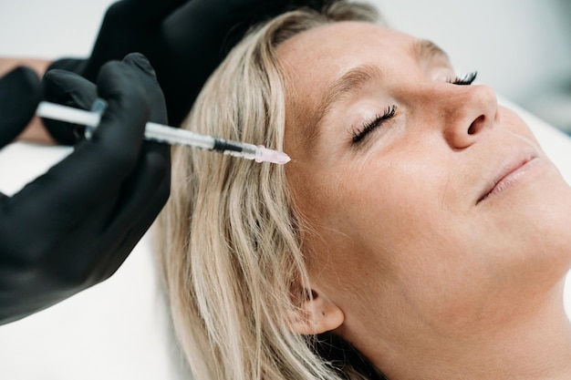 Foto mujer joven recibe inyecciones faciales de belleza en el concepto de cuidado de la piel del salón o clínica