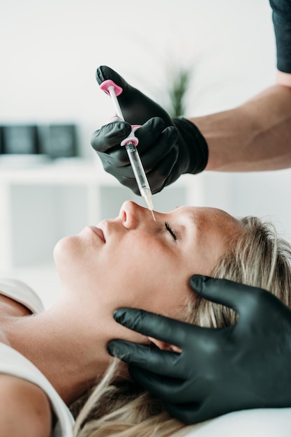 Mujer joven recibe inyecciones faciales de belleza en el concepto de cuidado de la piel del salón o clínica