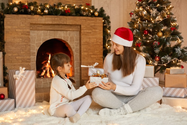 Mujer joven recibe regalo de Navidad de su linda hijita con dos coletas