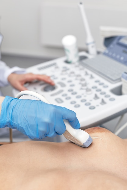 Mujer joven recibiendo un examen de mama por su ginecólogo, exploración por ultrasonido, tecnología de ecografía, equipos médicos, cuidado de la salud.