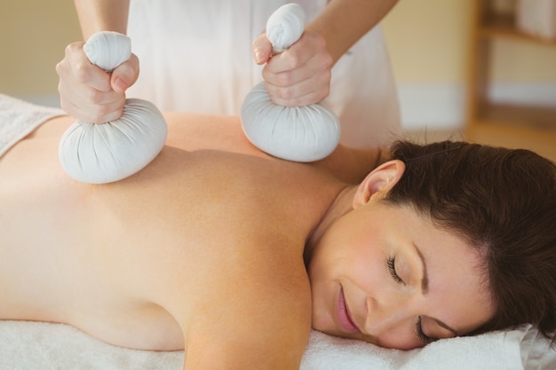 Mujer joven recibiendo masaje herbal compresa