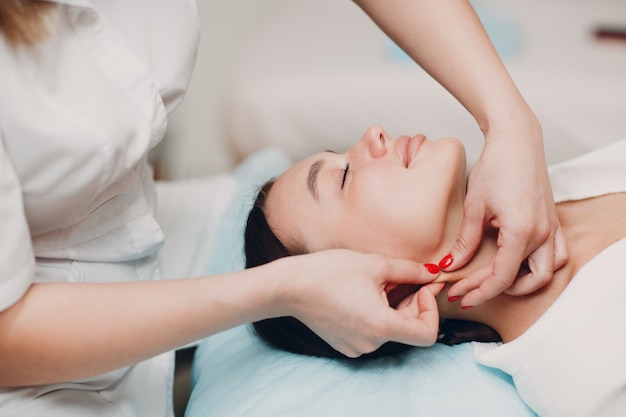 Mujer joven recibiendo masaje de tratamiento facial en el salón de belleza spa