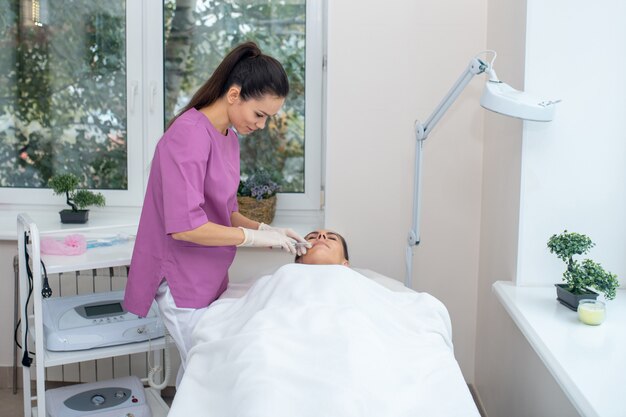 Mujer joven recibiendo un procedimiento facial en una clínica