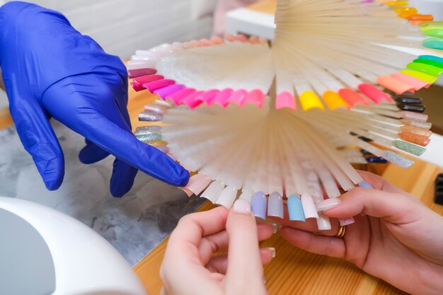 Mujer joven recibiendo un servicio de manicura en un salón de belleza. paleta de colores de barniz