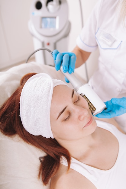 Mujer joven recibiendo tratamiento facial de endosferas en la clínica de belleza