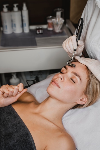 Foto mujer joven recibiendo un tratamiento facial