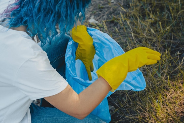 Mujer joven recogiendo basura y poniendo en bolsa de basura de plástico - concepto de contaminación ambiental