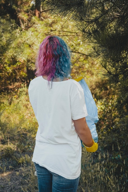 Mujer joven recogiendo basura y poniendo en bolsa de basura de plástico - concepto de contaminación ambiental