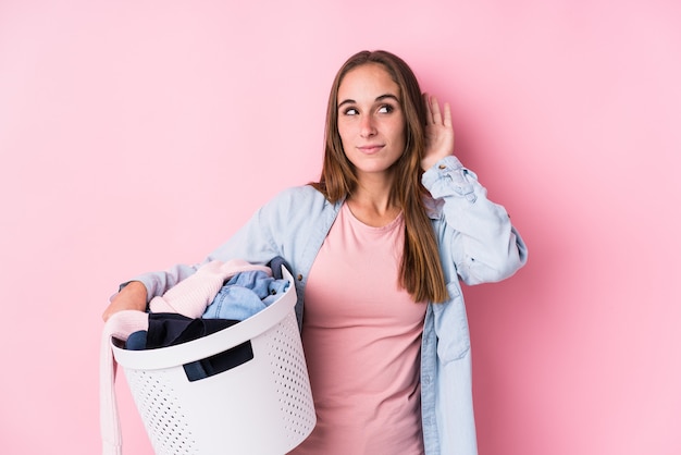 Mujer joven recogiendo ropa sucia tratando de escuchar un chisme