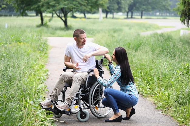 Mujer joven reconfortante marido en silla de ruedas apoyo en recuperación