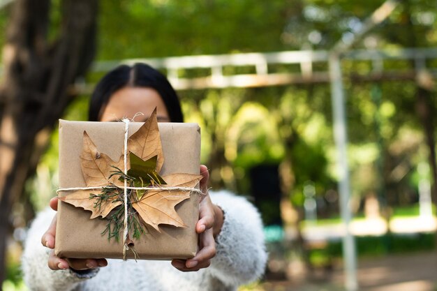 Foto mujer joven con regalo de navidad envuelto orgánico