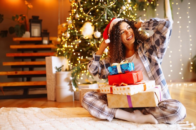 Mujer joven con regalos de Navidad en casa cerca del árbol de Navidad Vacaciones de invierno Año Nuevo