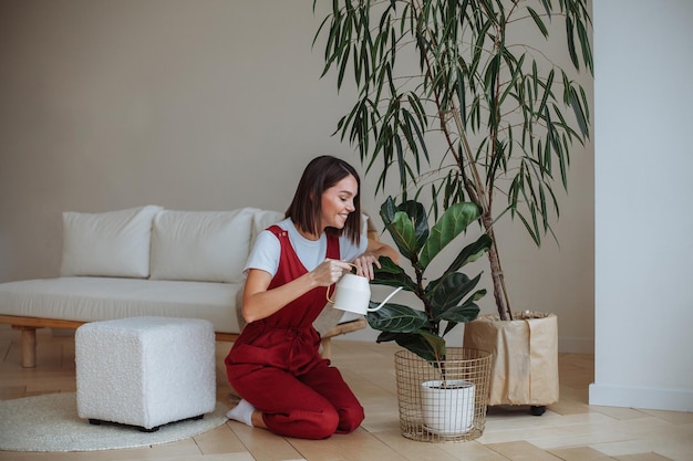 Mujer joven regando una planta en maceta en casa