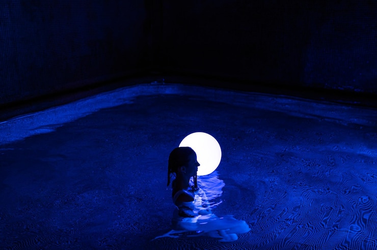 Foto mujer joven relajada en la piscina con luz de neón