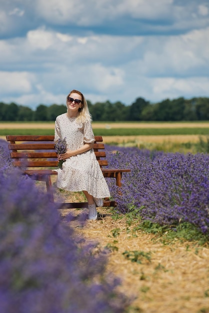 Mujer joven relajada sentada en un campo de lavanda un día soleado