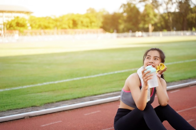 Mujer joven relajándose después del entrenamiento físico en el estadio de fútbol por la mañana con bengalas solares