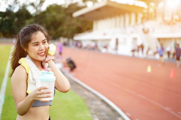 Mujer joven relajándose después del entrenamiento físico en el estadio de fútbol Tiene una hermosa sonrisa