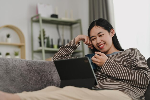 Foto mujer joven relajándose en el sofá en casa con los ojos cerrados y estirando los brazos disfrutando del tiempo libre