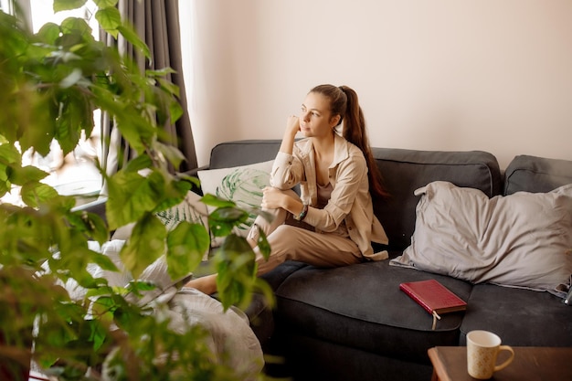 Mujer joven relajándose en el sofá y leyendo un libro