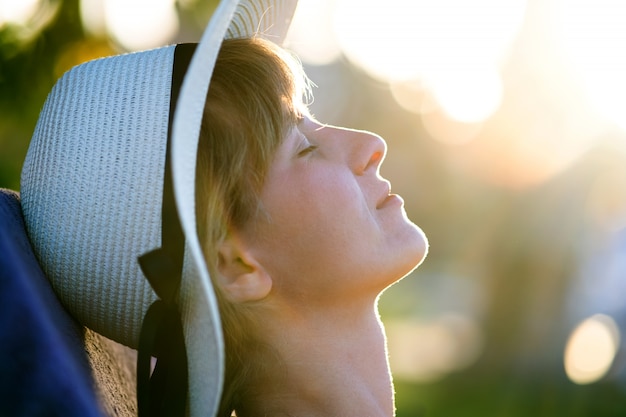 Mujer joven relajante al aire libre en un día soleado de verano.