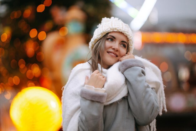 Mujer joven relajante bebiendo café en la feria festiva de Navidad Vacaciones de invierno Luces alrededor