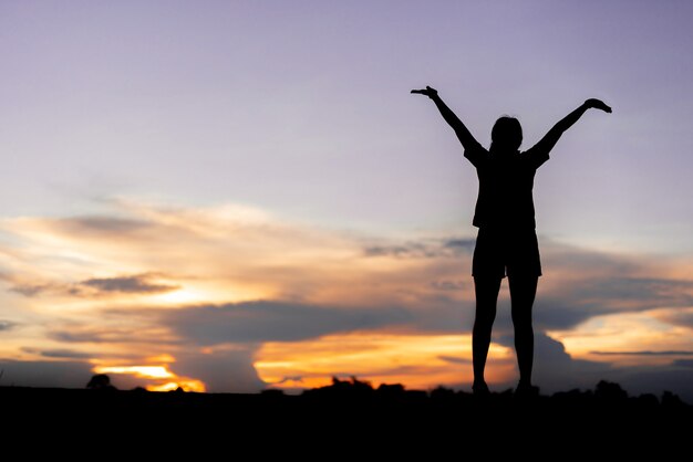 Mujer joven relajante con cielo al atardecer al aire libre.