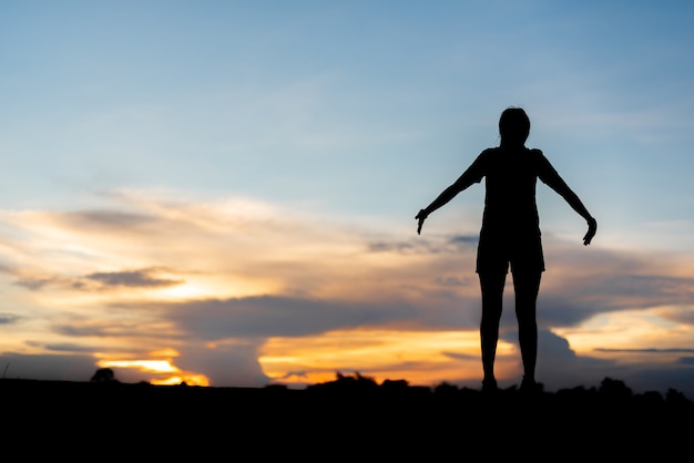 Mujer joven relajante con cielo al atardecer al aire libre.