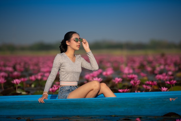 Mujer joven relajante con un hermoso campo de flores de loto en el Mar de Loto Rojo