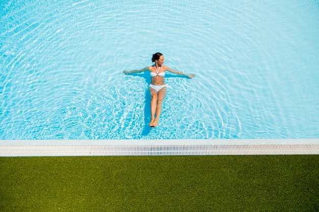 Mujer joven relajante en la piscina