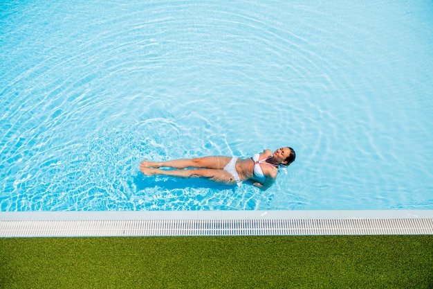 Mujer joven, relajante, en la piscina