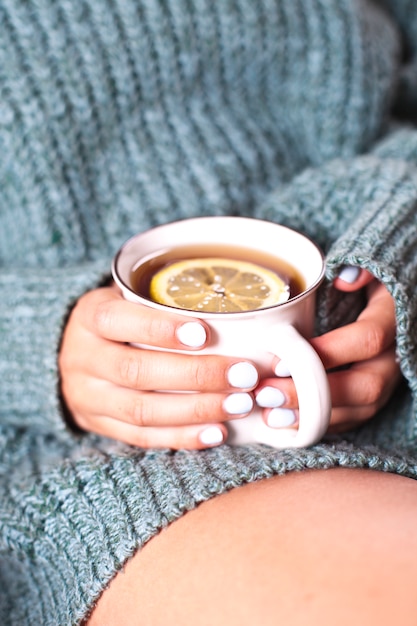 Mujer joven relajante con una taza de té en la mano