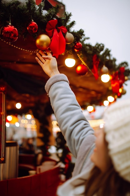 Mujer joven relajante tomando café en la feria navideña. Vacaciones de invierno. Luces alrededor.