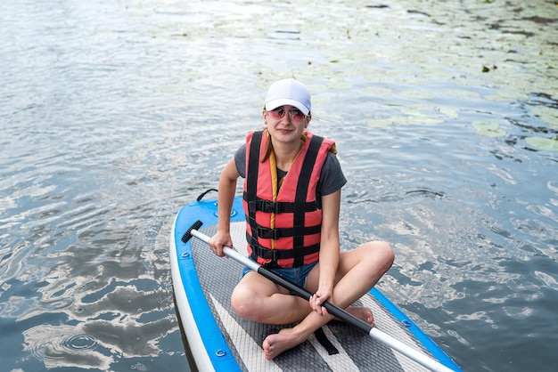 Mujer joven relajarse en SUP Stand up paddle board en verano