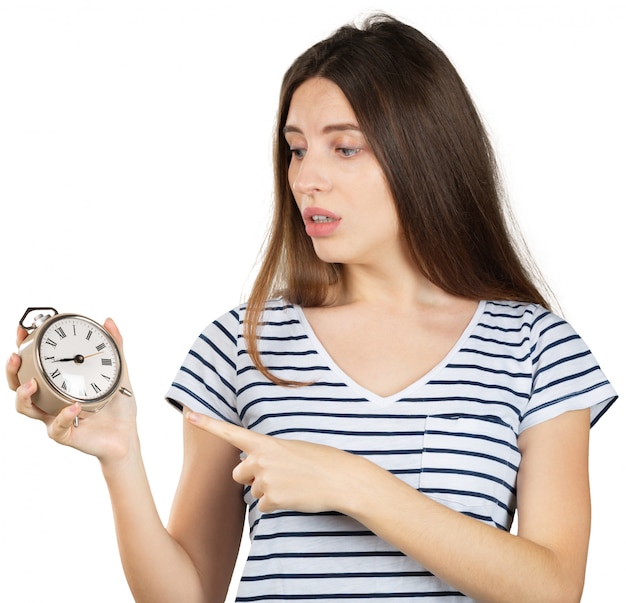 Mujer joven con el reloj de alarma aislado en blanco. Concepto de gestión del tiempo