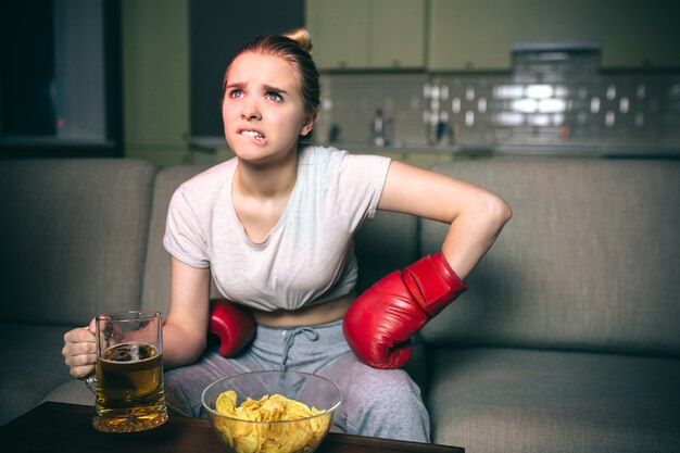 Mujer joven reloj de boxeo en la televisión por la noche.