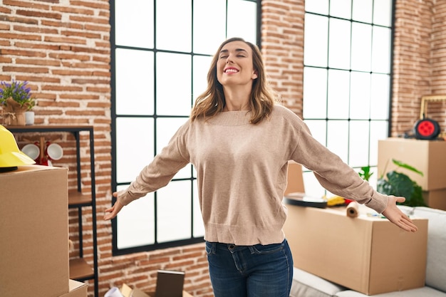 Foto mujer joven respirando con los brazos abiertos en su nuevo hogar