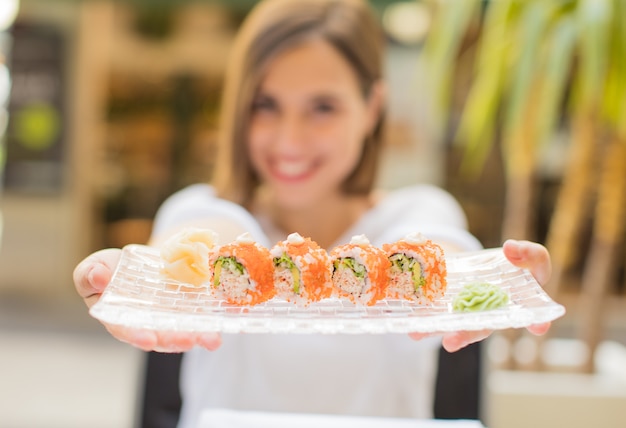 Foto mujer joven en un restaurante con sushi