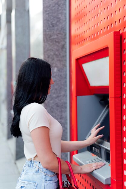 Mujer joven retirando dinero en cajeros automáticos