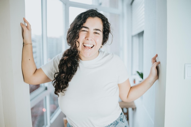 Mujer joven con retrato de pelo largo sonriendo y divirtiéndose en un piso moderno de la ciudad. Vida en la ciudad, concepto de vibraciones jóvenes. Libertad moviéndose solo desde el concepto de hogar de los padres