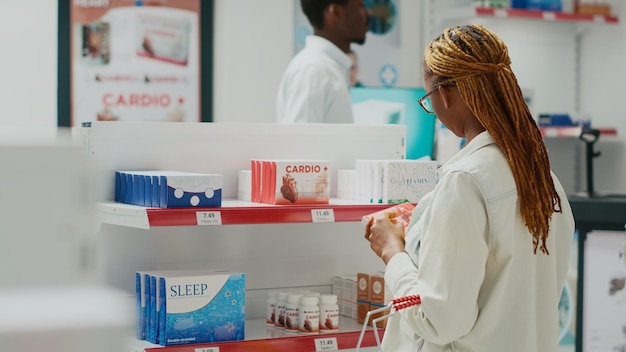 Mujer joven revisando la caja de pastillas en la tienda médica, mirando medicamentos en la tienda farmacéutica. Cliente comprando medicamentos recetados o tratamiento, leyendo folletos en paquetes de medicamentos.