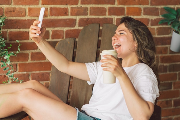 Mujer joven se ríe y habla por videollamada en el teléfono el concepto de movilidad en el estilo de vida