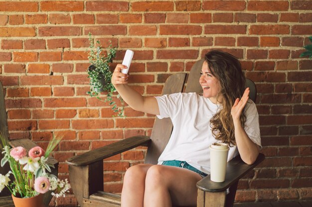 Mujer joven se ríe y habla por videollamada en el teléfono el concepto de movilidad en el estilo de vida