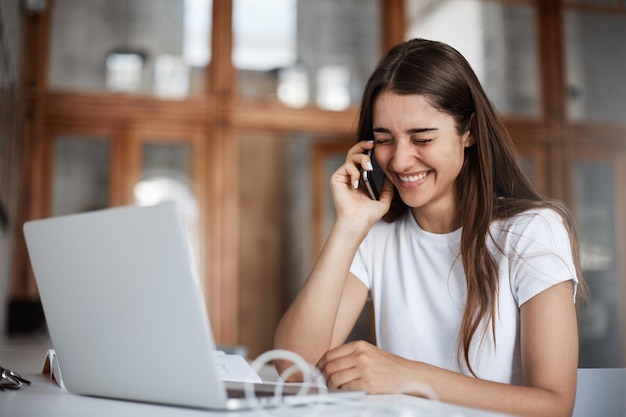 Mujer joven riendo hablando por teléfono con amigos discutiendo una fiesta de cumpleaños