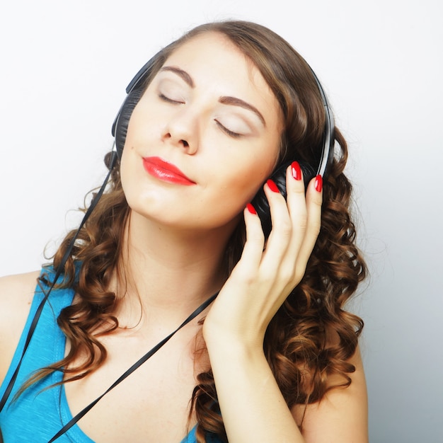 Mujer joven rizada con auriculares escuchando música.