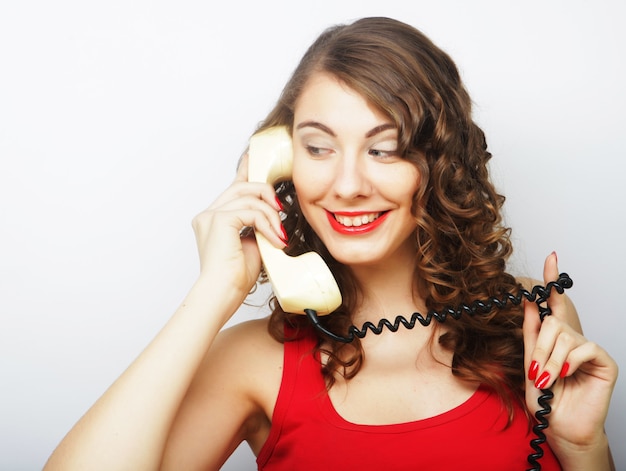 Mujer joven rizada con teléfono vintage.