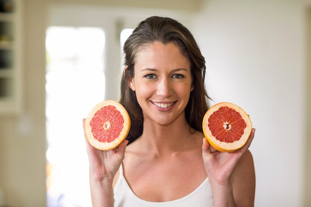 Mujer joven con rodajas de naranja de sangre en la cocina